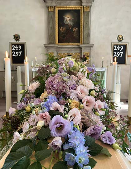 Begravning, kista med blommor och ljus.